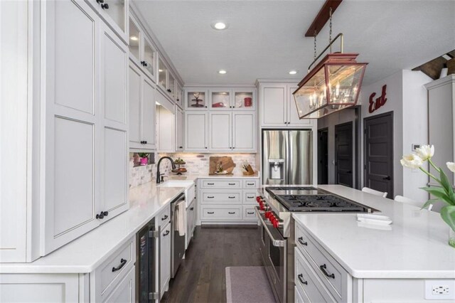 kitchen with white cabinetry, backsplash, stainless steel appliances, beverage cooler, and dark hardwood / wood-style floors