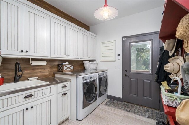 laundry area with cabinets, washer and clothes dryer, and sink