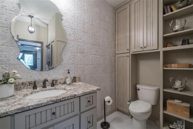 bathroom with tile walls, vanity, and toilet