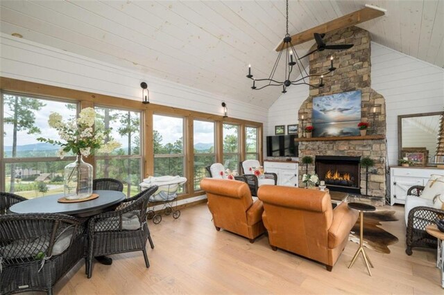 living room featuring beam ceiling, a stone fireplace, light hardwood / wood-style flooring, high vaulted ceiling, and wooden ceiling