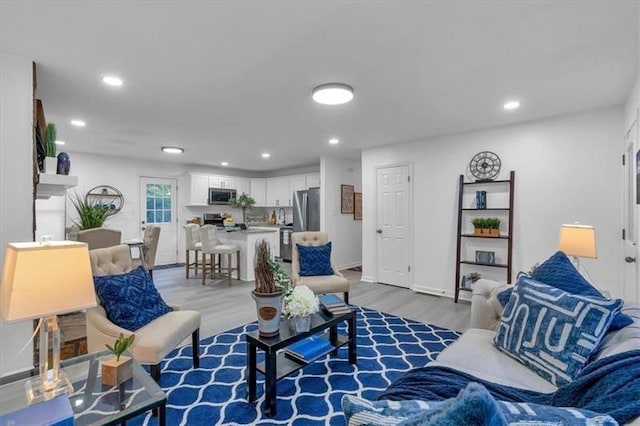 living area featuring light wood finished floors, baseboards, and recessed lighting