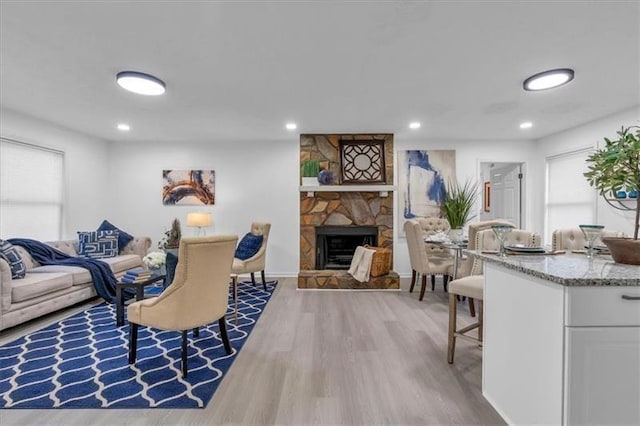 living area featuring a stone fireplace, wood finished floors, and recessed lighting