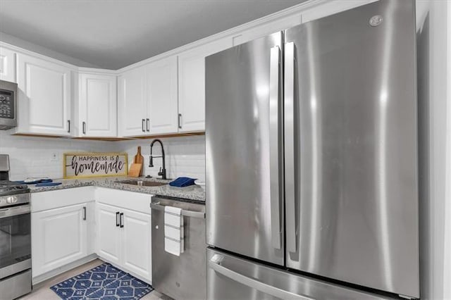 kitchen with stainless steel appliances, white cabinetry, a sink, and decorative backsplash