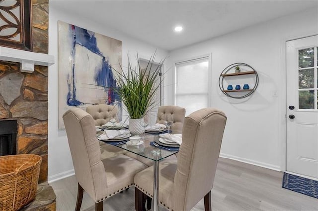 dining area with a fireplace, baseboards, wood finished floors, and recessed lighting