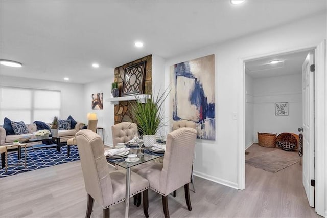 dining room with a fireplace, baseboards, wood finished floors, and recessed lighting