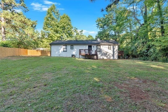 rear view of property with a wooden deck, fence, and a yard