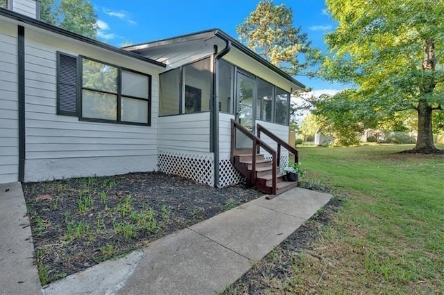 view of side of property featuring entry steps, a sunroom, and a yard