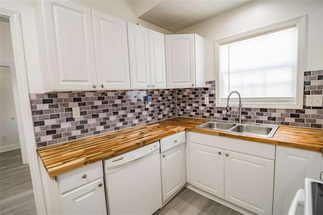 kitchen with a sink, dishwasher, wood counters, white cabinetry, and tasteful backsplash