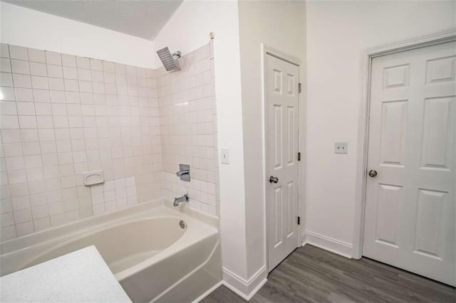 bathroom with baseboards, wood finished floors, and tub / shower combination