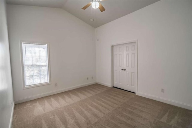 spare room featuring carpet floors, ceiling fan, vaulted ceiling, and baseboards
