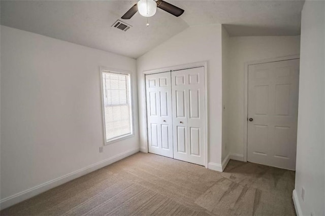 unfurnished bedroom featuring visible vents, baseboards, a closet, lofted ceiling, and carpet flooring
