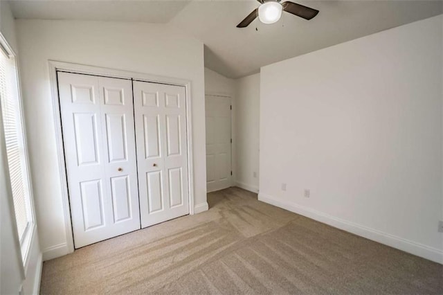 unfurnished bedroom with carpet floors, a closet, lofted ceiling, baseboards, and a ceiling fan