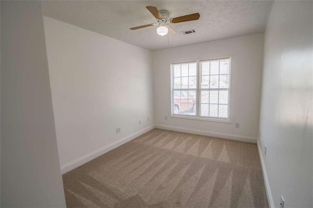 spare room with baseboards, ceiling fan, visible vents, and light colored carpet
