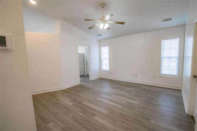 unfurnished room with ceiling fan, visible vents, wood finished floors, baseboards, and lofted ceiling