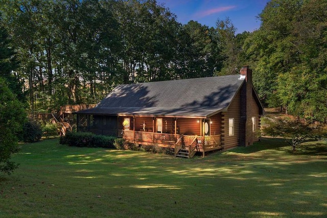 back house at dusk featuring a deck and a yard