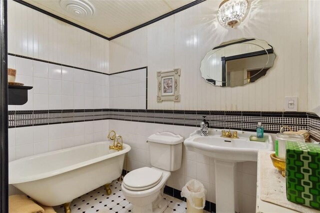 bathroom with toilet, tile walls, tile patterned floors, a bath, and sink