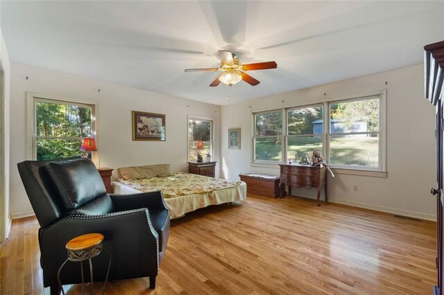 bedroom featuring light wood-type flooring, ceiling fan, and multiple windows