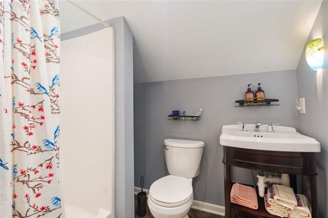 bathroom featuring sink, lofted ceiling, curtained shower, and toilet