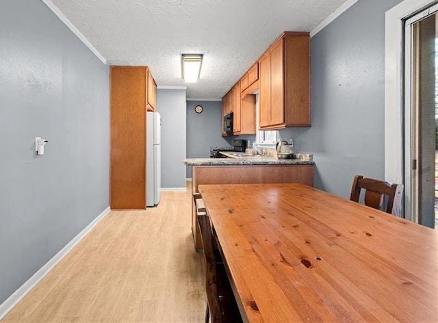 1729 Norden Rd, Riverdale, GA 30296 - kitchen featuring freestanding refrigerator, black microwave, light wood finished floors, brown cabinetry, and ornamental molding