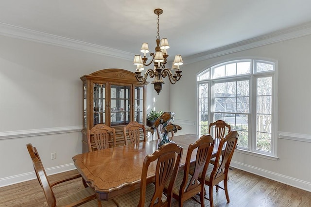 dining space with a notable chandelier, crown molding, and wood-type flooring