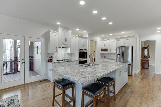 kitchen featuring sink, a breakfast bar area, appliances with stainless steel finishes, an island with sink, and white cabinets