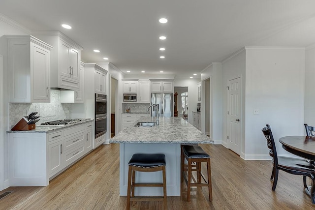 kitchen featuring white cabinetry, stainless steel appliances, sink, and an island with sink