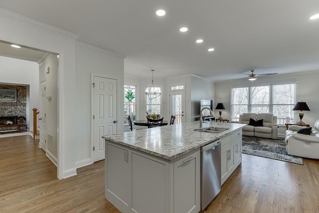 kitchen with sink, light stone counters, dishwasher, an island with sink, and white cabinets