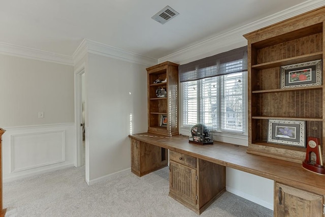 office area with ornamental molding, built in desk, and light carpet