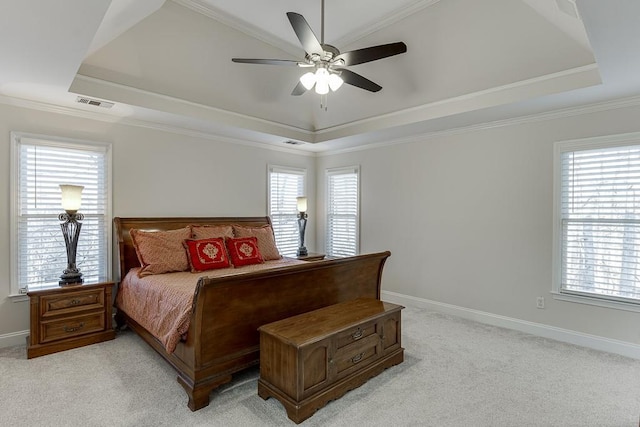 bedroom with multiple windows, light carpet, and a tray ceiling