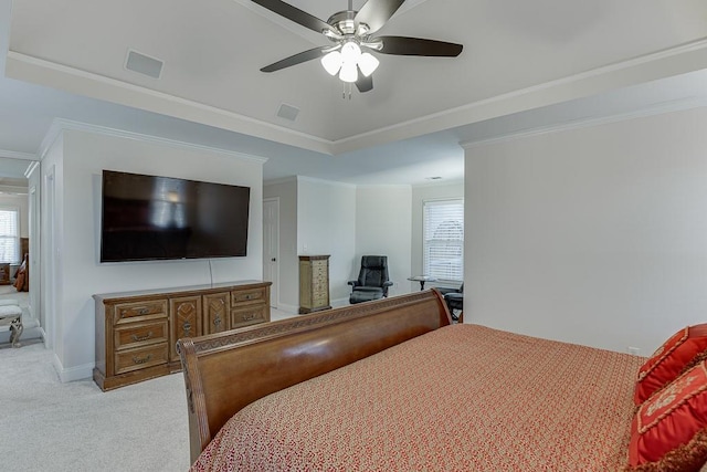 carpeted bedroom with a tray ceiling, ornamental molding, and ceiling fan