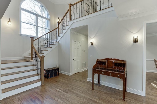 foyer featuring a high ceiling, crown molding, and hardwood / wood-style floors