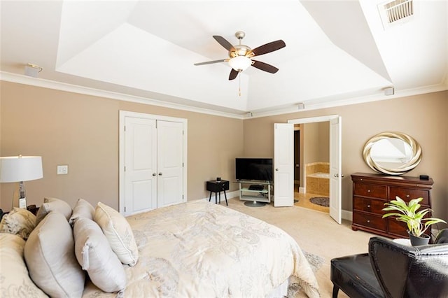 bedroom featuring light carpet, a tray ceiling, ceiling fan, crown molding, and a closet