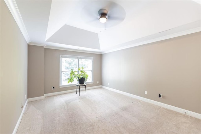 carpeted empty room with ceiling fan, ornamental molding, and a tray ceiling