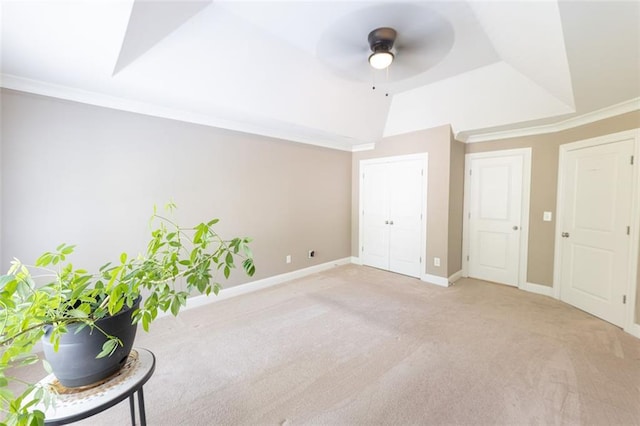 interior space with a raised ceiling, ceiling fan, and ornamental molding