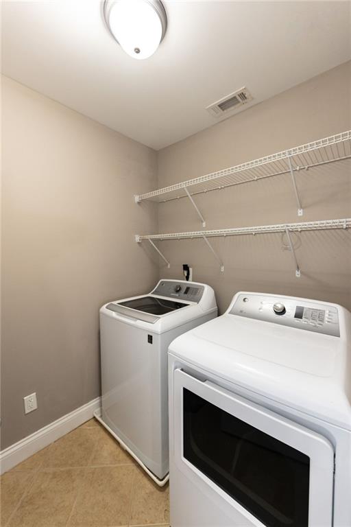 washroom featuring washer and clothes dryer and light tile patterned flooring