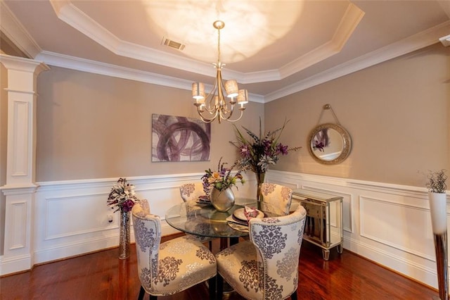 dining space featuring a tray ceiling, ornate columns, crown molding, and a notable chandelier