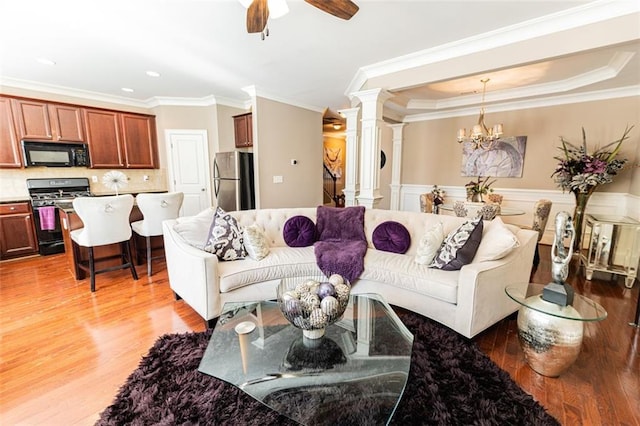 living room with decorative columns, crown molding, and hardwood / wood-style floors