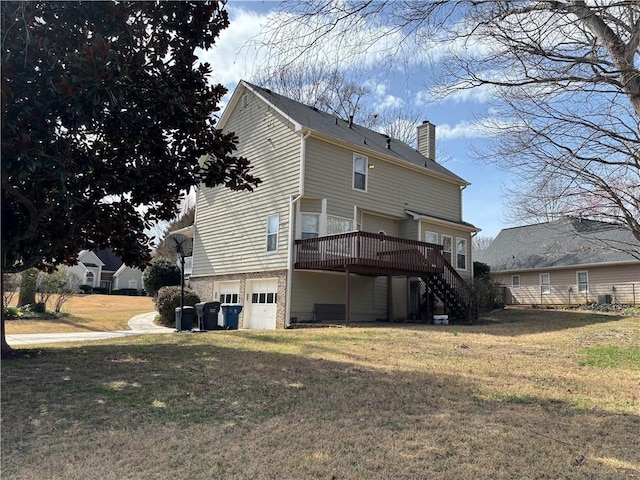 back of property with a garage, a lawn, a chimney, and stairs