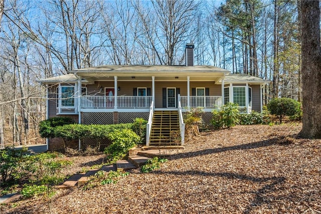 single story home featuring covered porch, stairs, and a chimney