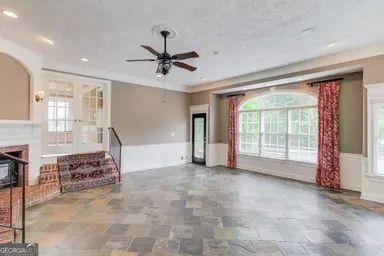 unfurnished living room with french doors, arched walkways, ceiling fan, and stone finish floor