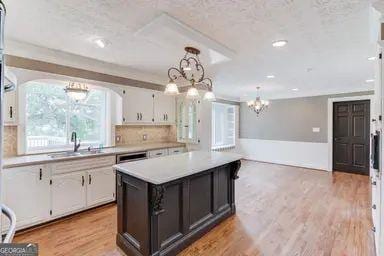 kitchen featuring an inviting chandelier, light countertops, a sink, and white cabinetry