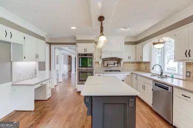kitchen with a sink, appliances with stainless steel finishes, backsplash, and light countertops
