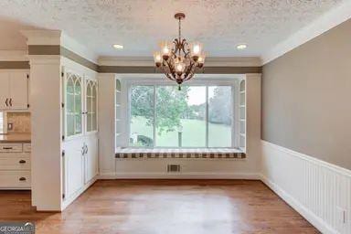 unfurnished dining area featuring light wood-type flooring, a textured ceiling, and a chandelier