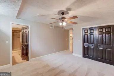 unfurnished bedroom with baseboards, ceiling fan, carpet floors, and connected bathroom