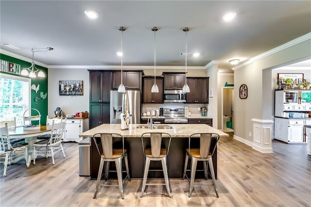 1412 Chapman Cir, Monroe, GA 30656 - kitchen with appliances with stainless steel finishes, ornamental molding, dark brown cabinetry, a breakfast bar area, and an island with sink