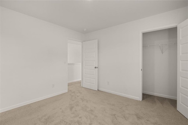 unfurnished bedroom featuring light colored carpet and a closet