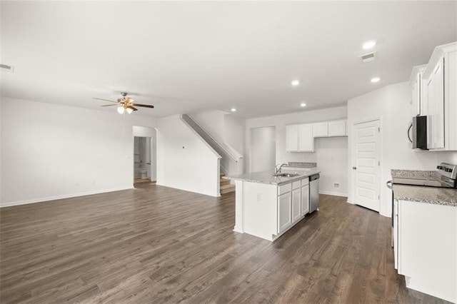 kitchen with stainless steel appliances, white cabinets, and an island with sink