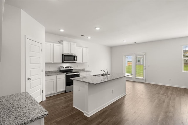 kitchen with light stone countertops, white cabinets, appliances with stainless steel finishes, sink, and a center island with sink