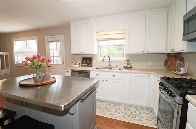 5415 Keithwood Dr, Cumming, GA 30040 - kitchen with white cabinets, a sink, light wood-style floors, stainless steel appliances, and a breakfast bar area