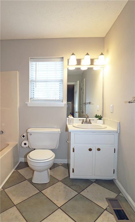 5415 Keithwood Dr, Cumming, GA 30040 - bathroom with a textured ceiling, vanity, visible vents, toilet, and tile patterned floors